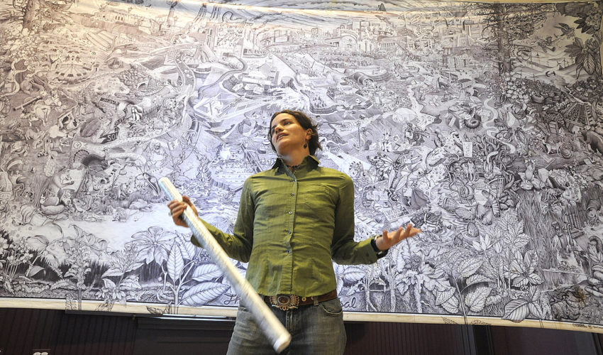 Emma Hornback, a member of the Machias-based Beehive Design Collective, speaks against the backdrop of a storytelling mural titled "The True Cost of Coal" at the Lewiston Public Library on Thursday.